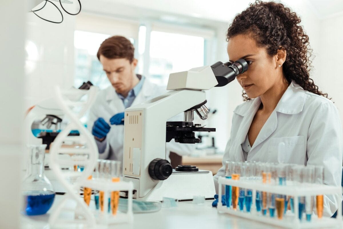 woman looking into microscope / scientific discoveries that changed the world