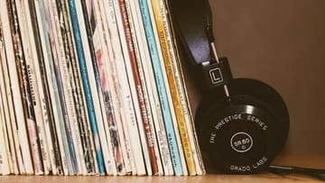 headphones leaning against vinyl records / 1980s movie soundtrack vinyl records