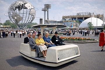 A bench with wheels taking people around a trades fair.