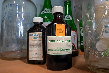 Old bottles of Coca Cola syrup on display with a collection of bottles at American Daydream Antiques & Miscellanea