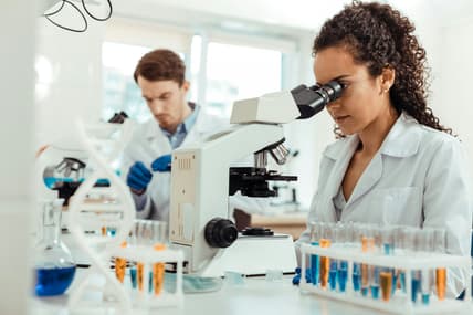 woman looking into microscope / scientific discoveries that changed the world