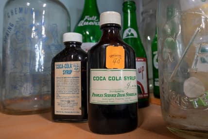 Old bottles of Coca Cola syrup on display with a collection of bottles at American Daydream Antiques & Miscellanea