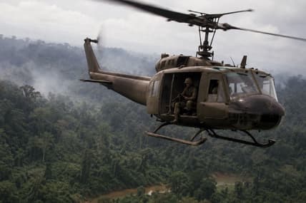Artist impression of Vietnam-era U.S. helicopter over jungle.