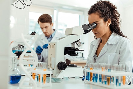 woman looking into microscope / scientific discoveries that changed the world