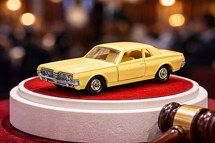 Matchbox car on pedestal, next to auction hammer.