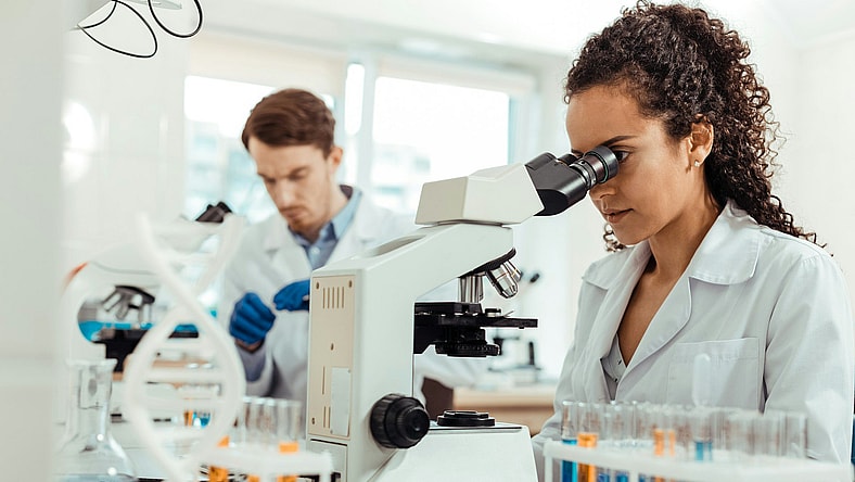 woman looking into microscope / scientific discoveries that changed the world