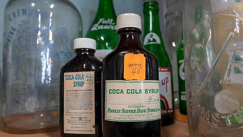 Old bottles of Coca Cola syrup on display with a collection of bottles at American Daydream Antiques & Miscellanea